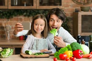Cooking Selfie. Joyful Young Dad Taking Photo On Smartphone With His Little Daughter In Kitchen While They Preparing Healthy Lunch Together, Panorama