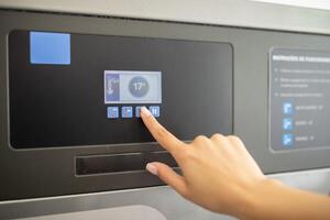 A person is pressing buttons on a touch screen control panel, likely adjusting settings in a facility. The interface displays temperature and additional options clearly. photo