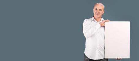 Happy Mature Man Showing Vertical Blank Placard With Copy Space For Your Text Isolated Over Blue Studio Wall photo
