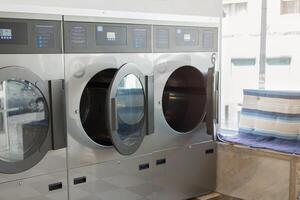 Bright and airy laundromat features shiny washing machines in a row, while neatly folded towels sit atop a nearby surface, creating a tidy atmosphere for laundry day. photo