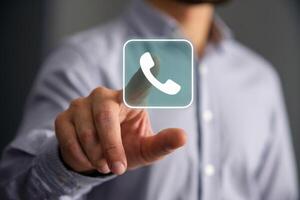 Hand points at a phone icon on a blurred background photo