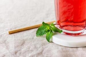 Red berries and fruits drink in the glass on the light background. photo