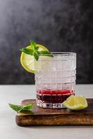 Cocktail with ice in a glass on a wooden cutting board photo