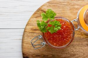 Red caviar in jar with fresh parsley photo