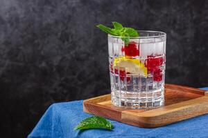 Raspberry cocktail with ice in a glass on a wooden tray photo