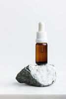 Serum in the brown bottle for face on white marble. photo
