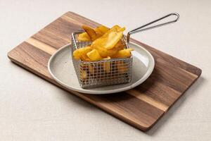 French fries in a metal basket on a wooden board photo