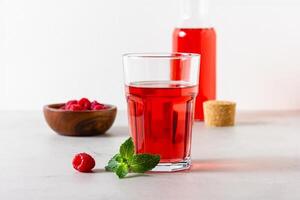 Raspberry drink in the glass on the light background. photo