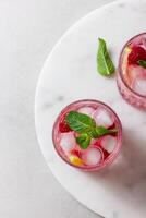 Raspberry cocktail with ice in a glass on a light background photo