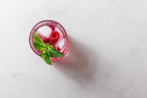 Raspberry drink with ice in a glass on a light background photo