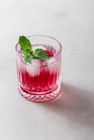 Raspberry cocktail with ice in a glass on a light background photo