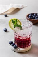Cocktail with ice and blueberry in a glass on marble photo