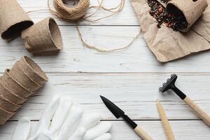 Gardening. Tools for garden and eco pots with ground on white wooden background. photo