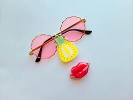 Pineapple icon and round original pink glasses with red lipstick in a case on a white background photo