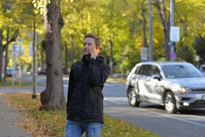 A man talking on a phone at the street on a sunny autumn day. A man uses a mobile smartphone device photo