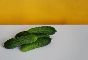 Small fresh young cucumbers at yellow background photo