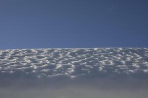 The snow on the roof. Snow and sky. Melting of the snow layer. photo
