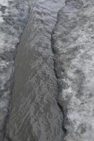 Dirty water flows on asphalt. Flow of water along road. Cloudy liquid. photo
