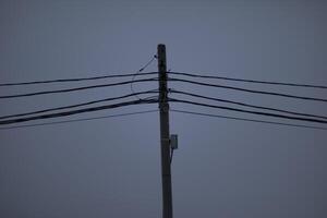 Wires on pole. Electrical wires on background of gray sky. Depressing look. photo