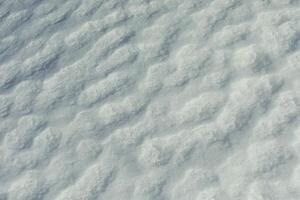 Texture of snow. Melted snow in winter in sun. Surface is wavy. photo