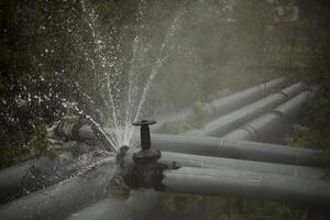 Burst pipe. Water pouring. Pipeline accident. It's dangerous situation. photo