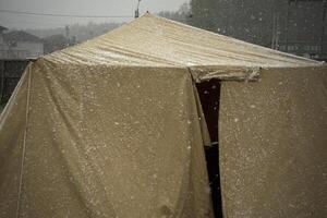 Military tent in the snow. Tent for the shelter of soldiers. The first snow on the tent. photo