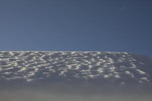 The snow on the roof. Snow and sky. Melting of the snow layer. photo