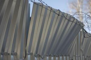 Broken fence. Crumpled steel profile. Damage to the fence. photo