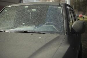 The car is in the dust. Dirt on the body of the vehicle. Black car in the parking lot. photo