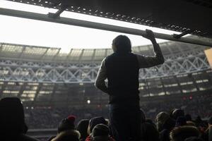 Guy at stadium. Silhouette of man against background of stadium. Mass event and one person. photo