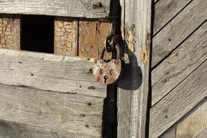 Old lock on the door. Rusty lock on the barn. The old building in detail. photo