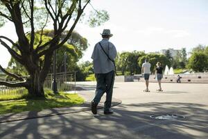 Guy walks through park in summer. Walking around city on summer day. Man from behind on street. photo