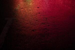 Red light on wet asphalt. Asphalt in a red glow in the evening. Empty parking space. photo