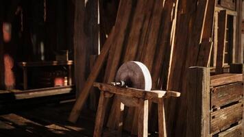 Wooden grinding wheel resting on a rustic bench in a workshop at dusk video