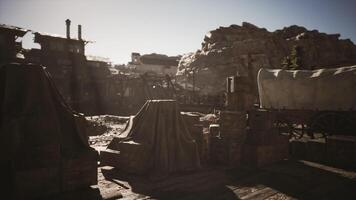 Old western settlement with weathered wagons and wooden crates at sunset video