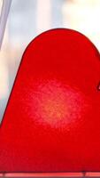 Bright lamp in shape of heart is on window. Concept. Red heart-shaped lamp stands at window and glows to bestow love on everyone. Bright romantic decor video