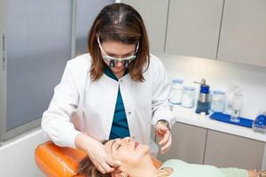 Dermatologist making a routine checkup on a senior famale patient using a binocular loupe. photo
