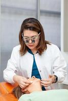 Dermatologist making a routine checkup on a senior famale patient using a binocular loupe. photo