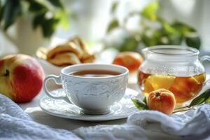 A cup of tea and a bowl of apples on a table photo