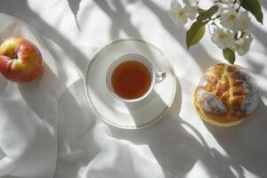 A cup of tea and a pastry on a white table photo