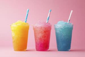 Three colorful drinks in plastic cups on a pink background photo