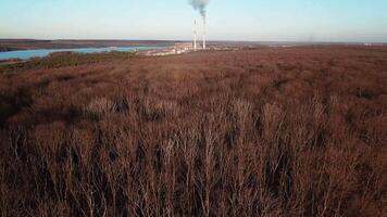 power station is working on the background of the river and the forest in the autumn. Aerial view video