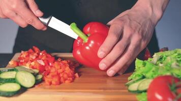 Chef in Black Uniform is Slicing Red Paprika and Preparing Vegetable Ingredients for Cooking. Man in a Kitchen is Cutting Red Pepper for Vegetarian Dish. Healthy Food Concept video