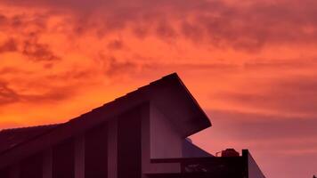 A red sky with clouds and a house in the foreground photo