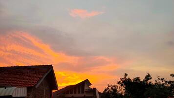 A sunset over a house with a red roof photo