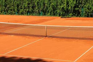 Tennis court with a sand surface and a stretched net for playing a sports game with a ball and rackets photo
