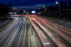City road background with automobile light trails blurred headlights in the evening photo