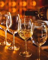 Bartender pouring white wine into glasses at bar counter photo