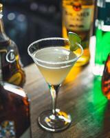 Cocktail glass standing on bar counter with bottles in background photo