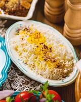 Saffron rice being served on floral plate on a rustic table setting photo